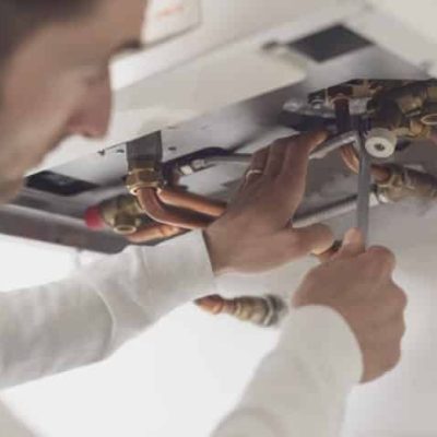 Professional plumber checking a boiler and pipes, he is using a wrench