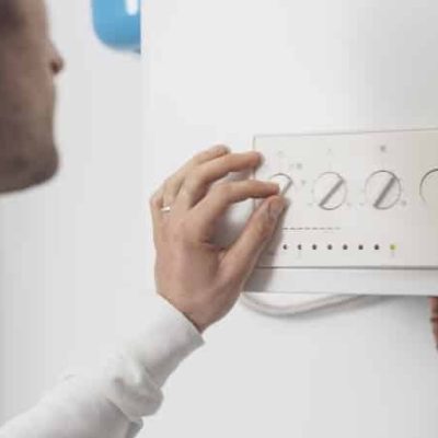 Professional plumber checking a boiler control panel, he is adjusting a knob